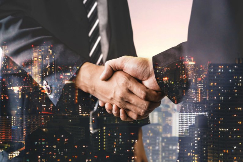 Businessmen shaking hands with a city skyline in the background