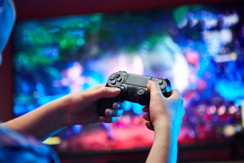 Gracz trzymający kontroler gier wideo przed telewizorem