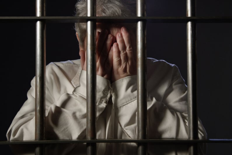 Ältere Frau hinter Gittern