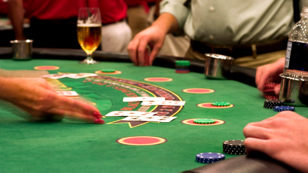 Physical casino blackjack table with people placing bets.