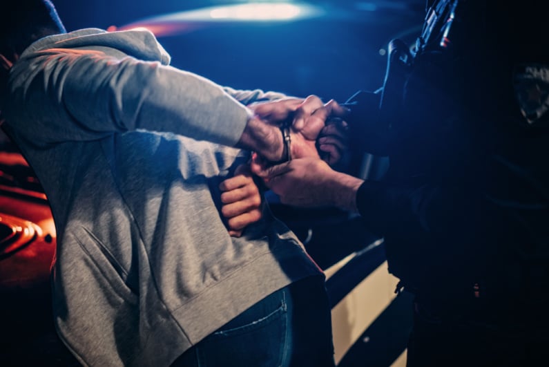 Полицейский надевает наручники на подозреваемого