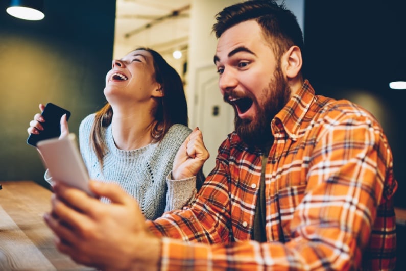 Couple looking at phone and celebrating